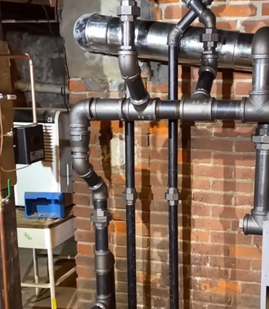 Steam near-boiler piping against a brick basement wall