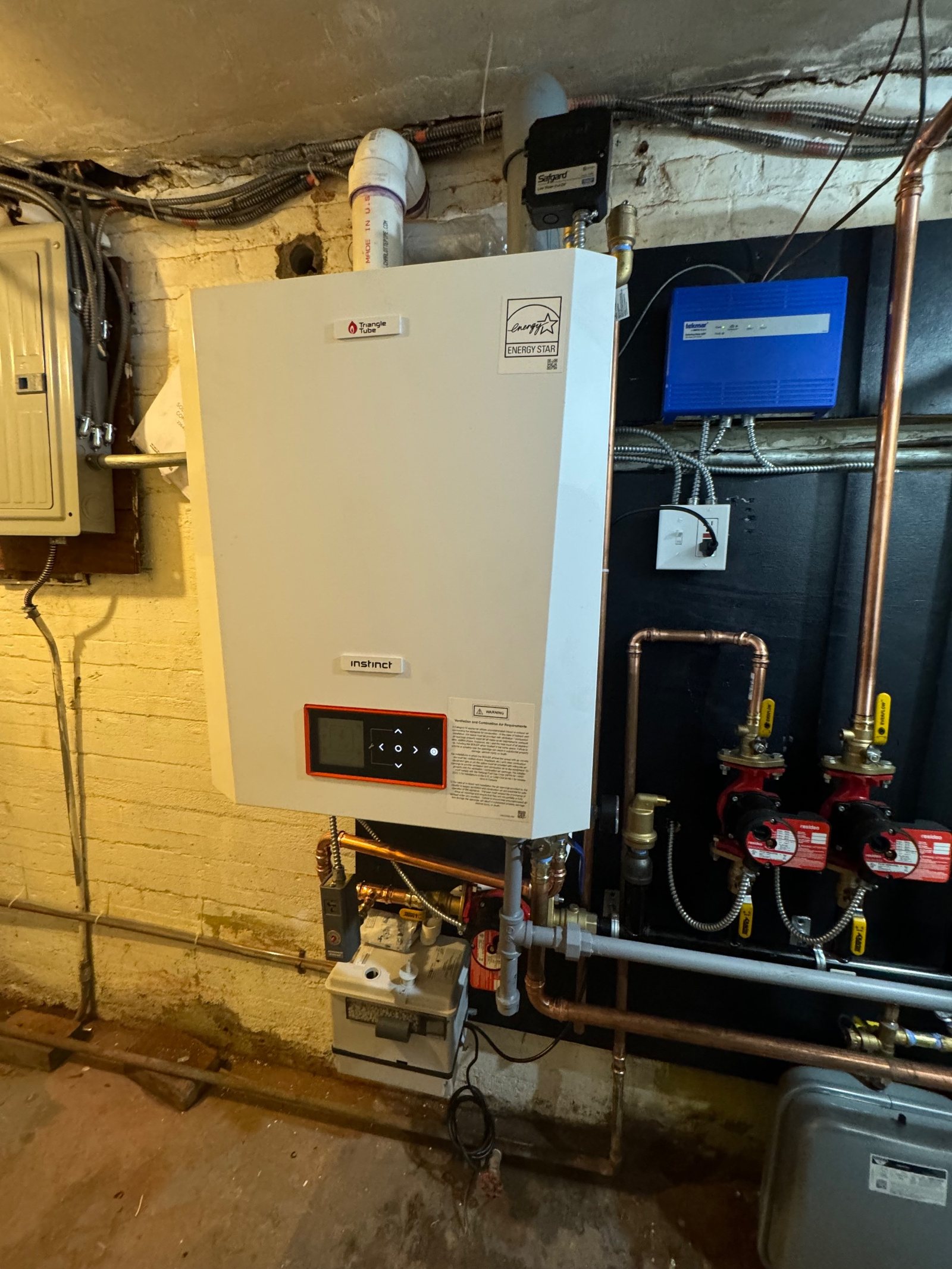 A wall-hung boiler and hot water cylinder in a basement