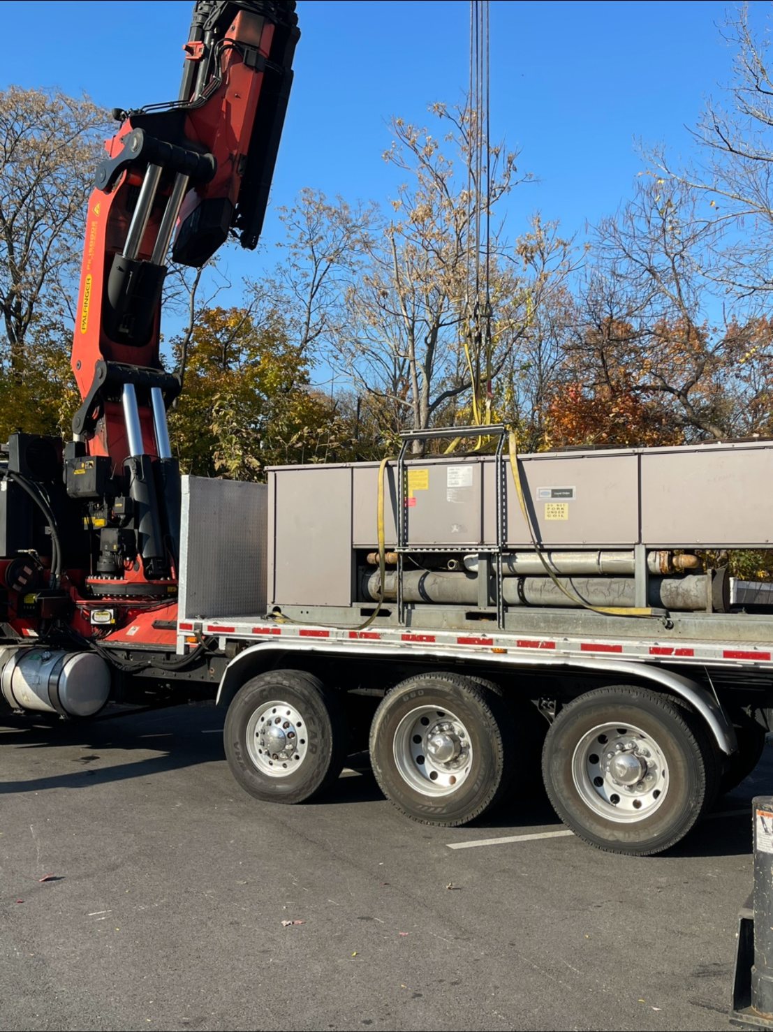 A rooftop air handling unit on a flatbed with a crane