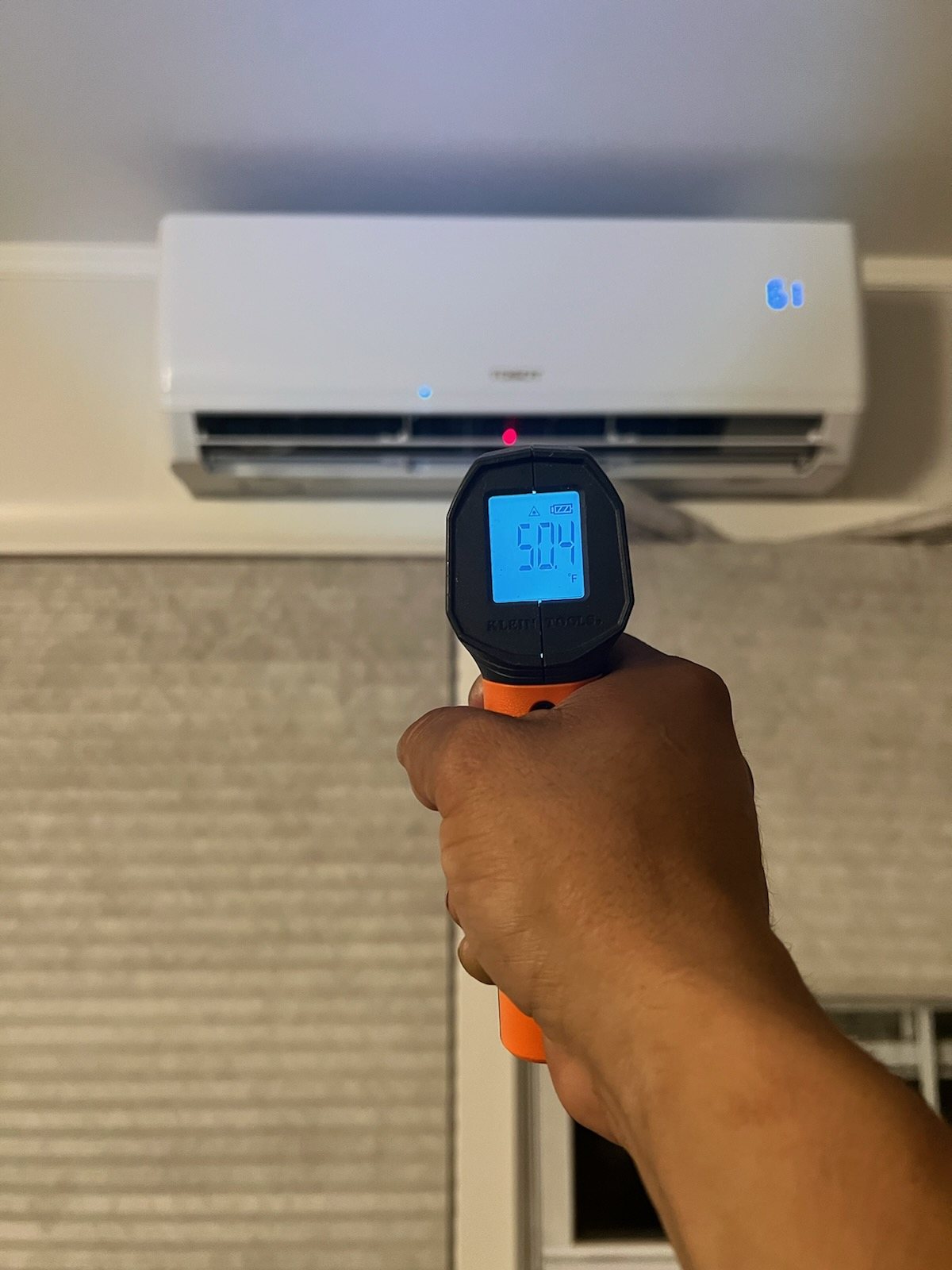 An infrared thermometer reading the supply air at a ductless head